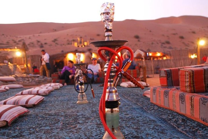 Immerse yourself in the unique desert charm enjoying shisha under the stars surrounded by cozy seating and the soft glow of lights all before an unforgettable night of entertainment.